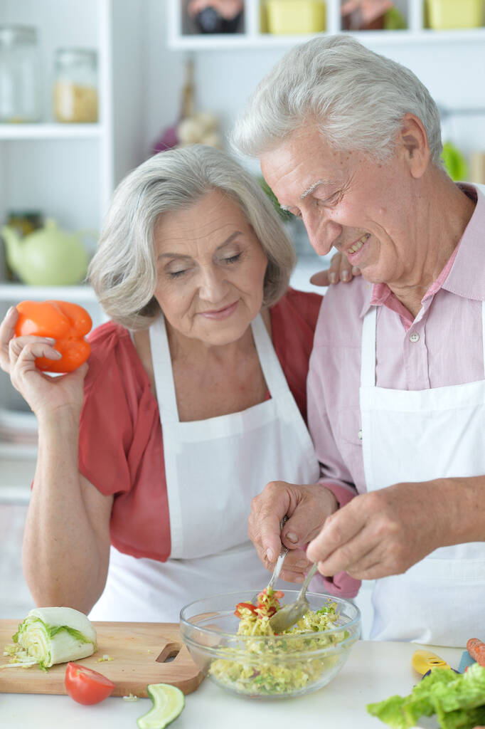 gelukkig senior paar maken salade samen in de keuken - Foto, afbeelding