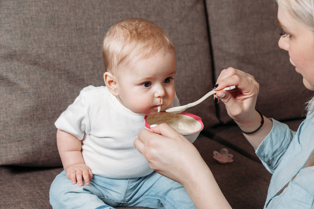young mother feeds her daughter with a spoon of fruit puree - Photo, Image