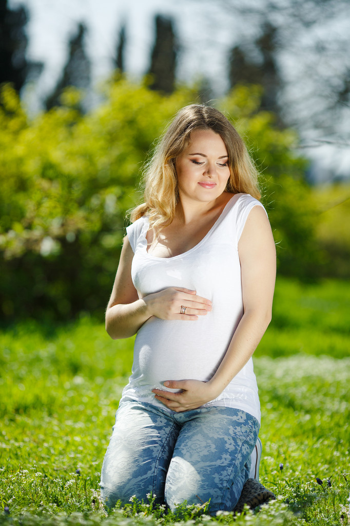 Portret gezonde zwangere vrouw zittend op groen gras - Foto, afbeelding