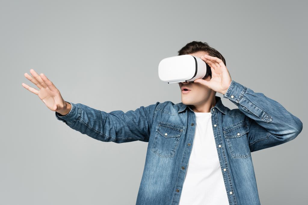 Hombre excitado usando auriculares de realidad virtual aislados en gris - Foto, Imagen