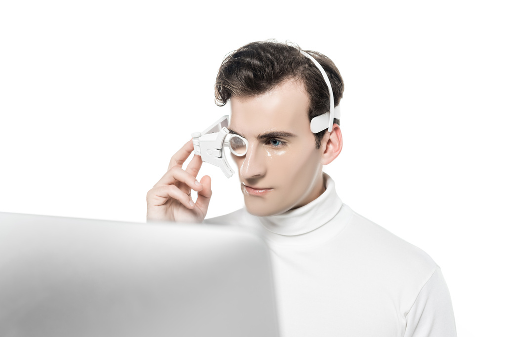 Kyborg v oční čočky a sluchátka při pohledu na počítač na rozmazané popředí izolované na bílém - Fotografie, Obrázek