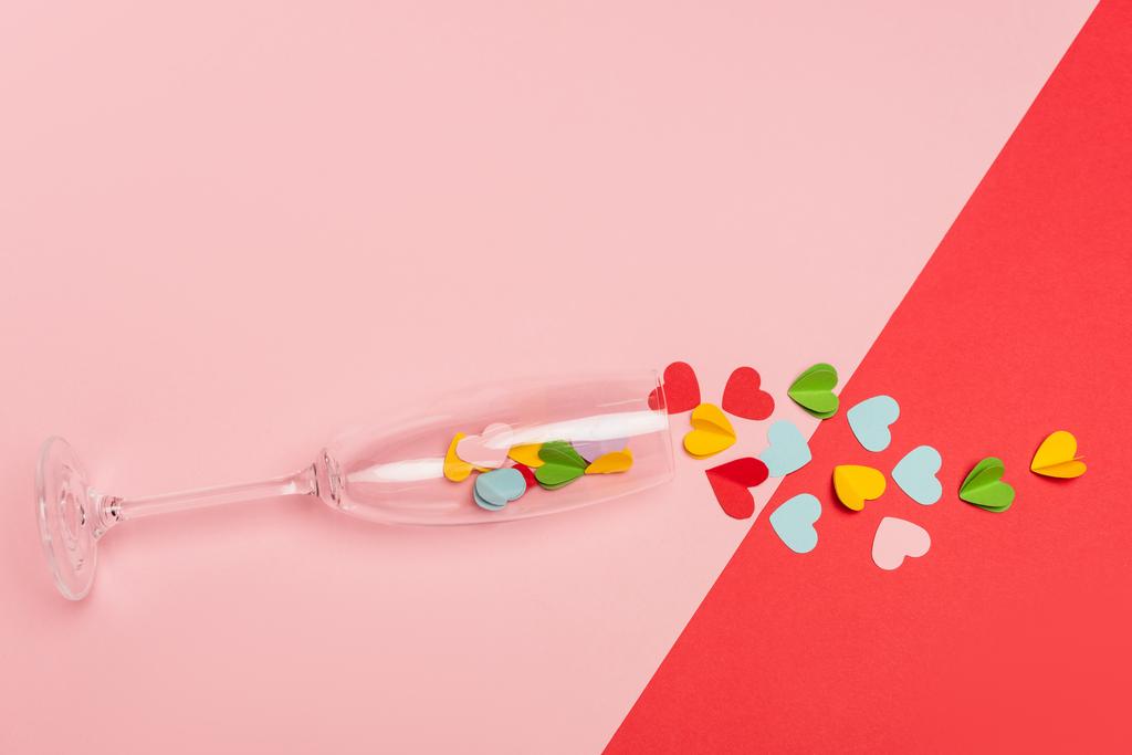 Draufsicht auf Sektglas mit Herzen auf rosa und rotem Hintergrund - Foto, Bild