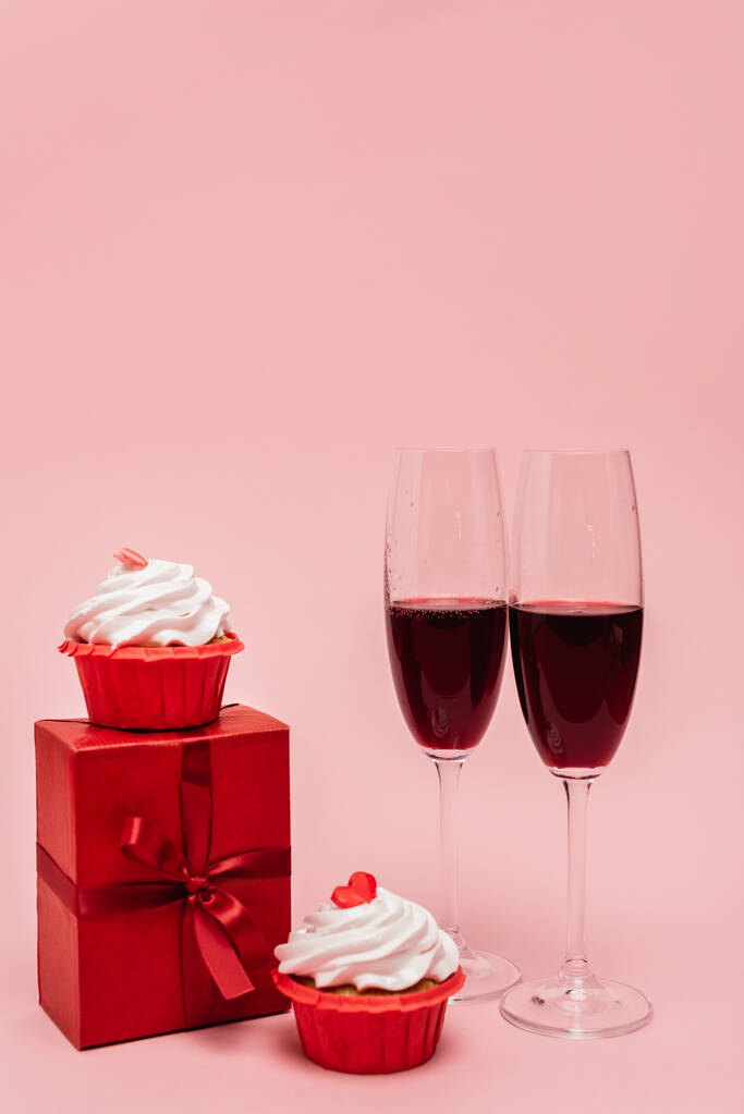 vino rosso vicino regalo e cupcake isolati su rosa - Foto, immagini
