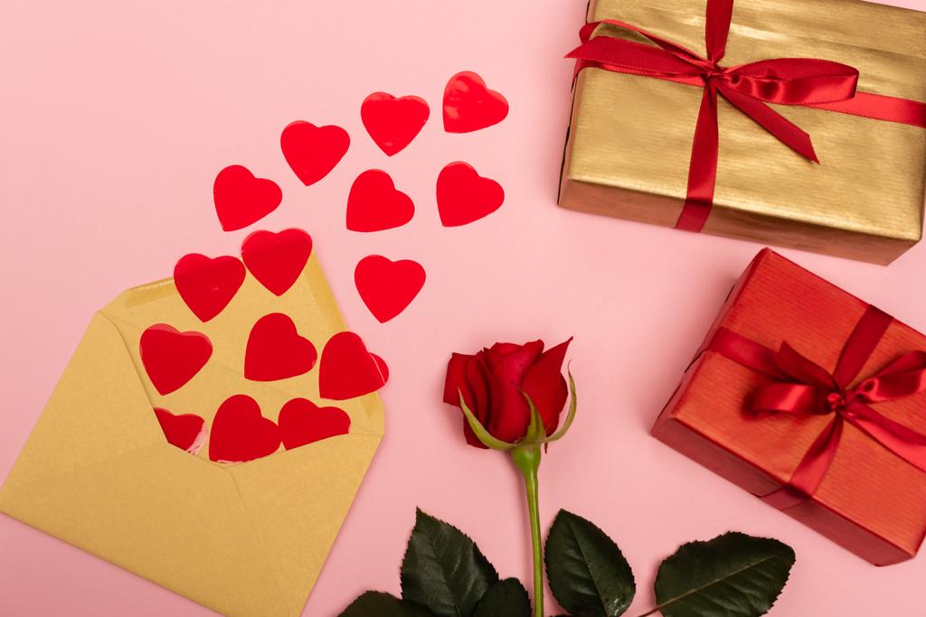 вид зверху на червоні серця, троянду, конверт і подарункові коробки на рожевому фоні
 - Фото, зображення