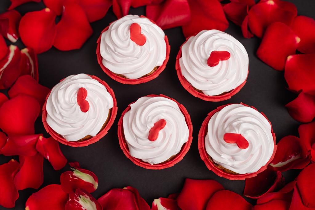 vista superior de pétalas de rosa e cupcakes valentines isolados em preto - Foto, Imagem