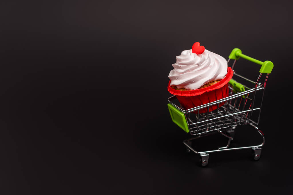 shopping cart with valentines cupcake isolated on black - Photo, Image