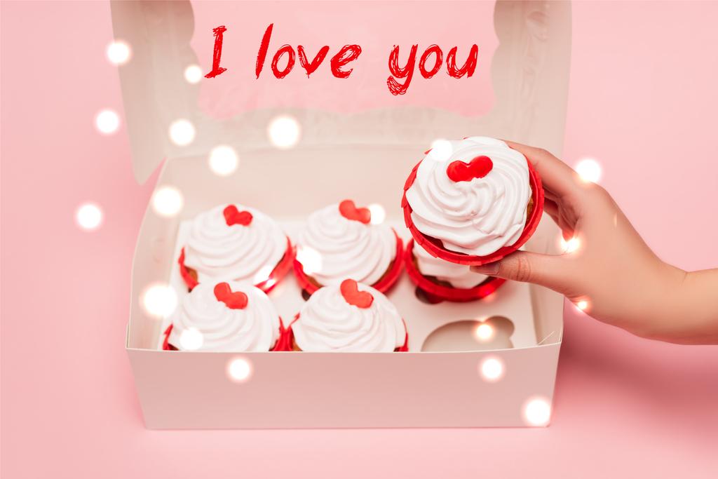 rajattu näkymä nainen tilalla Ystävänpäivä cupcake lähellä ruutua ja rakastan sinua kirjoitus vaaleanpunainen tausta - Valokuva, kuva
