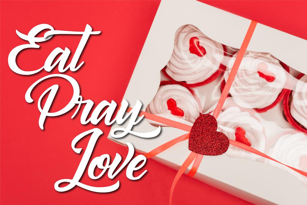 Ansicht der Schachtel mit leckeren Cupcakes in der Nähe von eat pray love Schriftzug auf rot - Foto, Bild