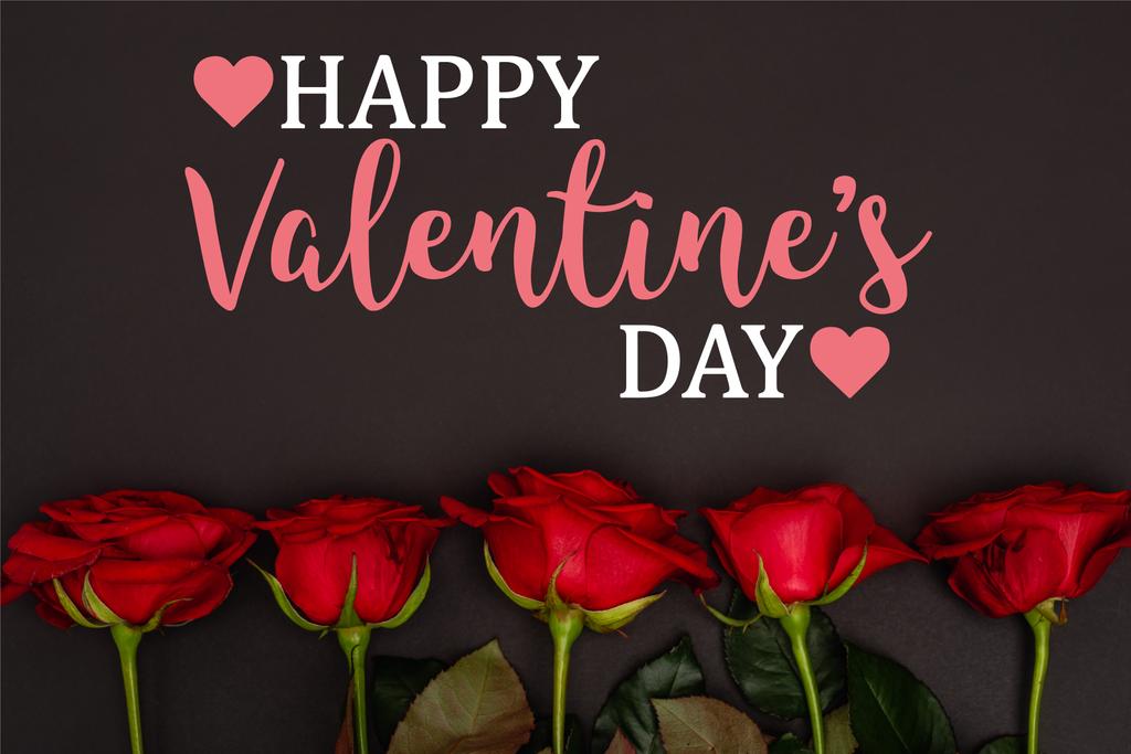 vista dall'alto di rose rosse vicino felice giorno di San Valentino lettering su nero - Foto, immagini