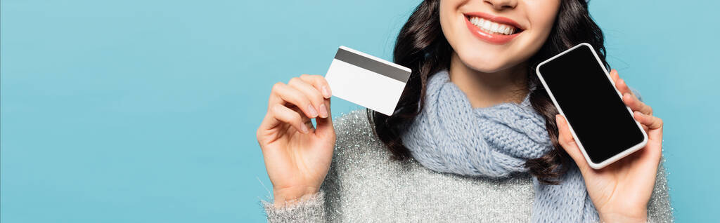 Eşarp takan bir kadının elinde kredi kartı ve mavi pankartta izole edilmiş beyaz ekranlı akıllı telefon görüntüsü. - Fotoğraf, Görsel