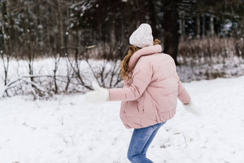 divertida foto en vivo de una chica corriendo en un parque cubierto de nieve - Foto, Imagen