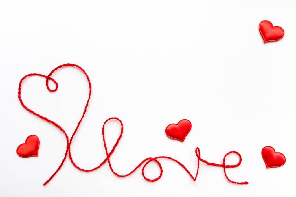 Concepto de San Valentín. Corazón rojo y palabra amor hecha de cuerda de lana sobre fondo blanco con espacio para copiar - Foto, imagen