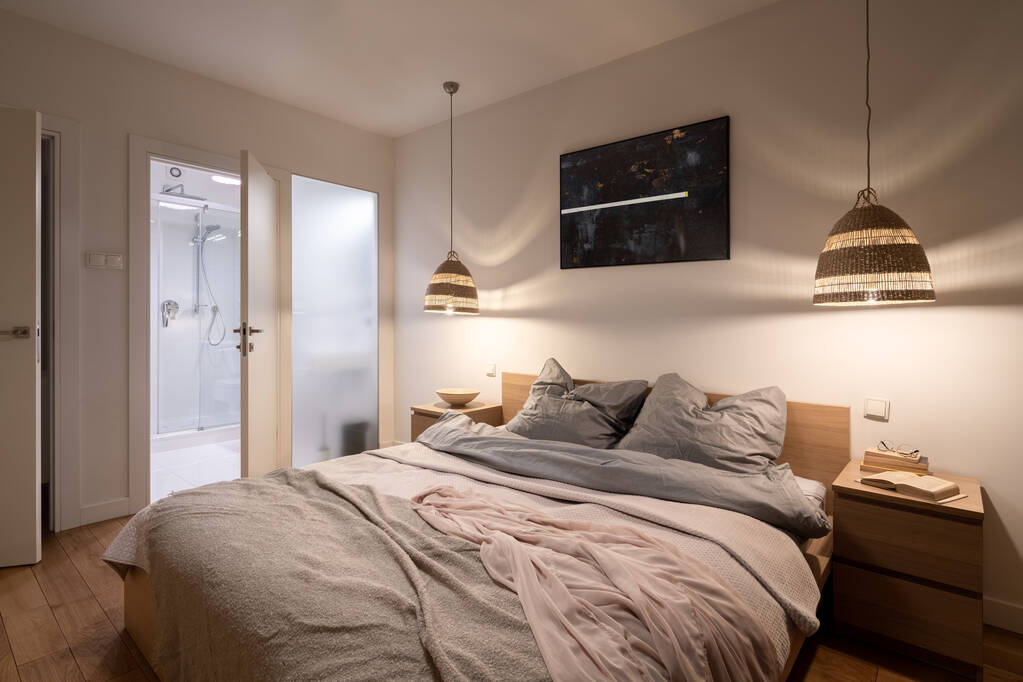 Quarto confortável e espaçoso com cama grande, mesas de cabeceira de madeira, lâmpadas de vime e banheiro atrás da parede de vidro fosco - Foto, Imagem