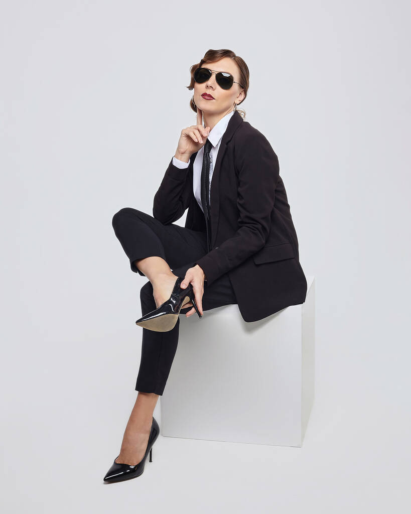 attractive woman with a retro hairstyle poses in a men's suit and sunglasses - Photo, Image