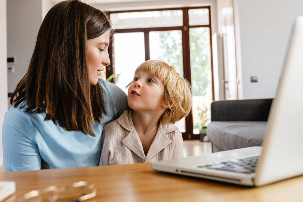 Photo of young positive beautiful woman at home with her son using laptop computer - Photo, Image