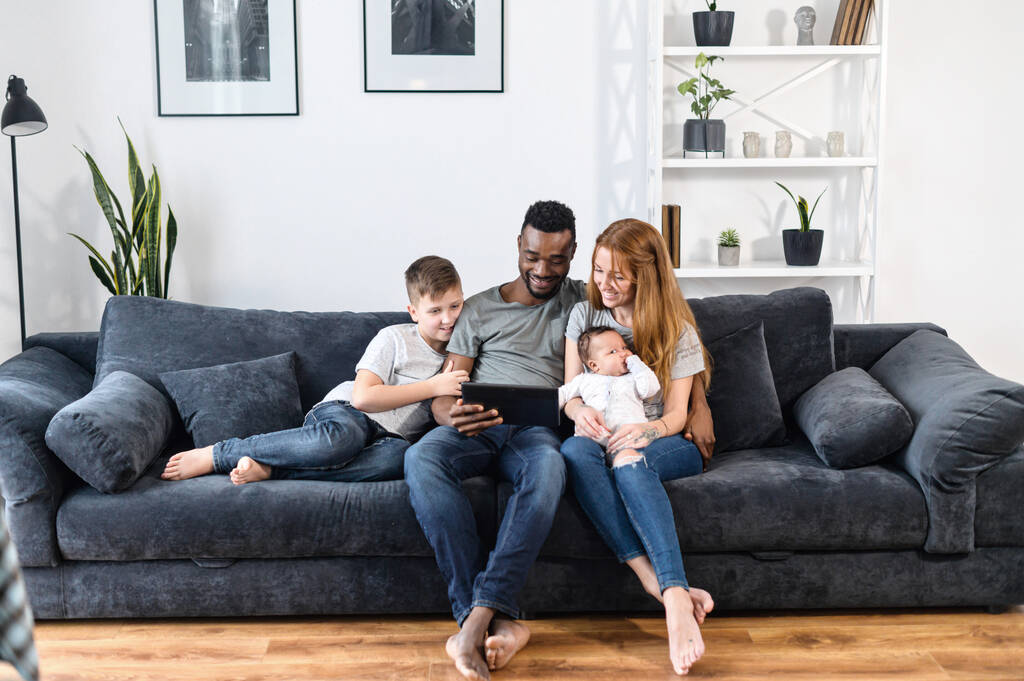Une famille multiraciale sur le canapé à la maison - Photo, image