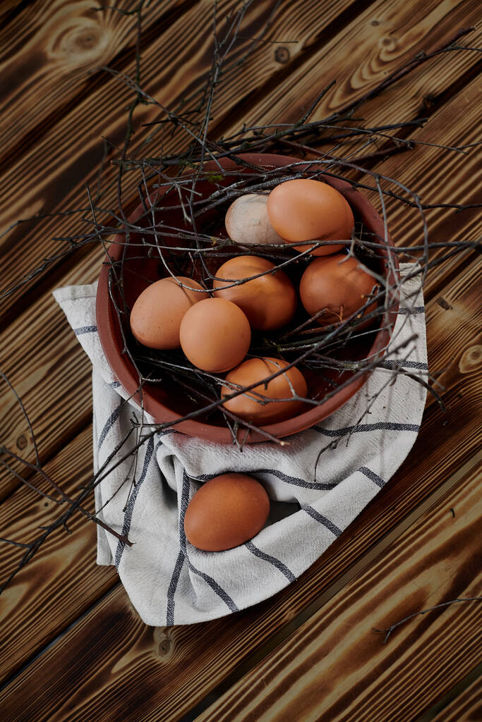 csirke tojás barna tál ágak fa asztal és ruha csíkos - Fotó, kép