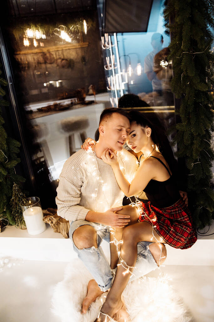 若いカップルはクリスマスにガーランドと恋に落ち  - 写真・画像