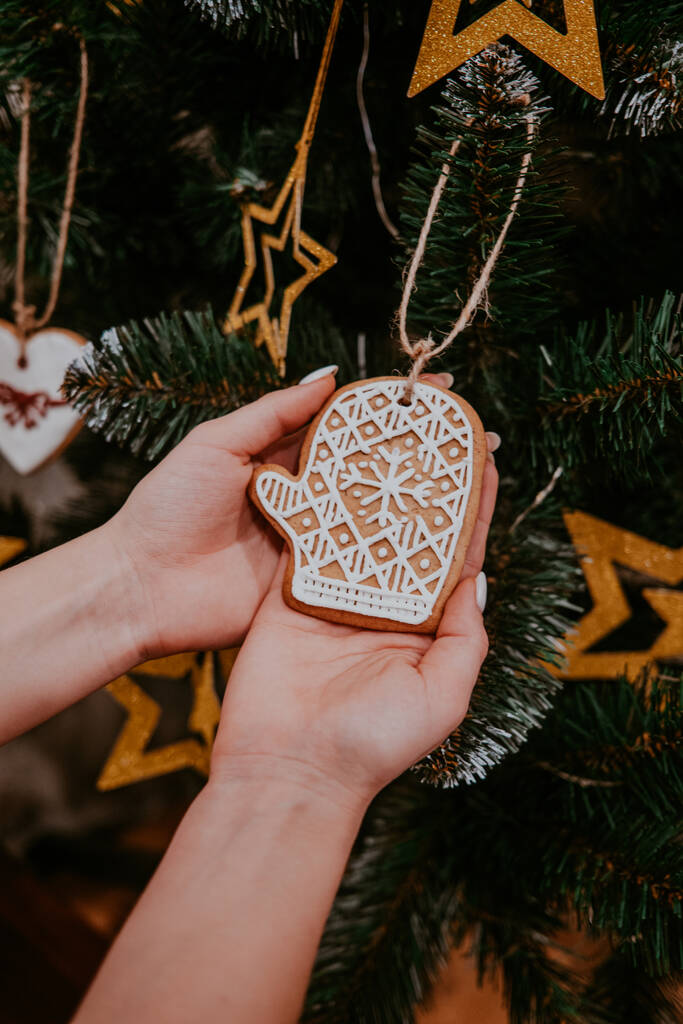 Woman decorating Christmas tree with gingerbread mitten cookie. Holiday concept. - Photo, Image