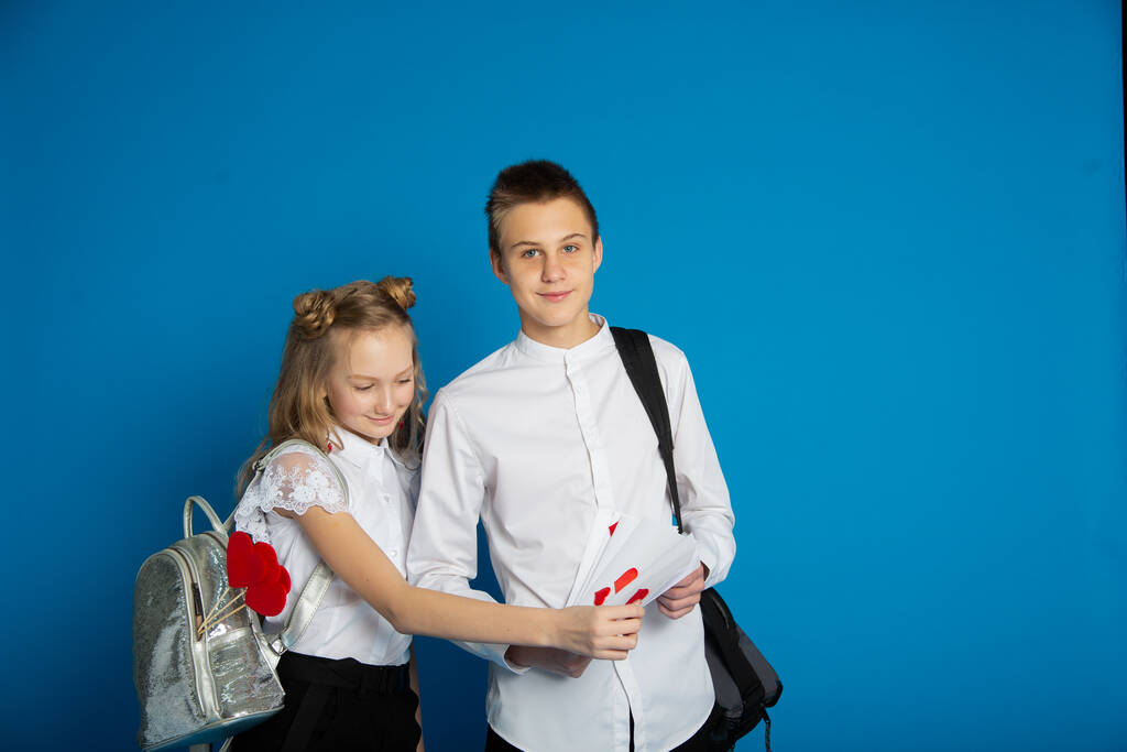 Para uczniów to nastolatki w Walentynki na niebieskim tle. - Zdjęcie, obraz