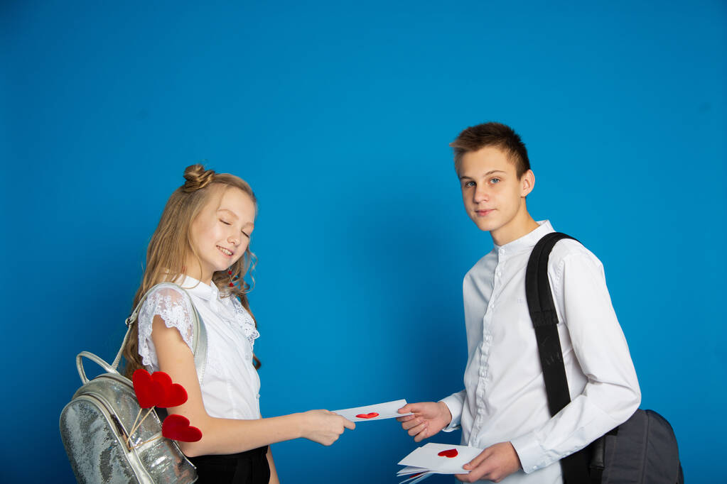 A couple of schoolchildren are teenagers on Valentine's Day on a blue background - Photo, Image