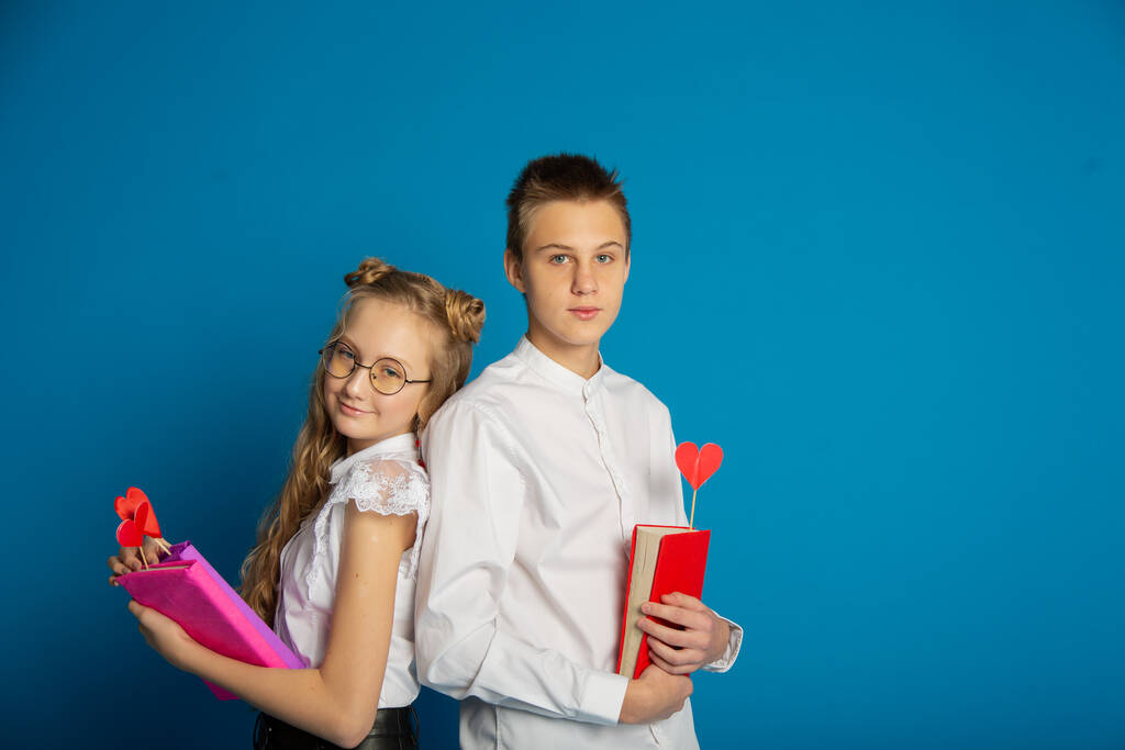Ein paar Schulkinder sind Teenager am Valentinstag vor blauem Hintergrund - Foto, Bild
