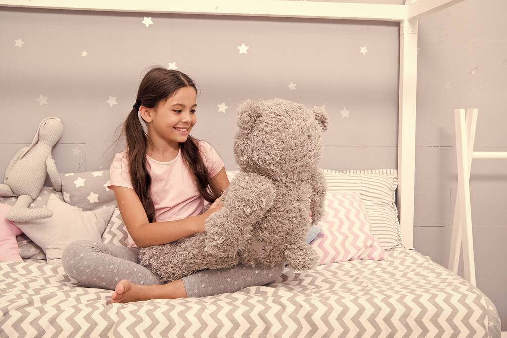 Spielen. Lieblingsspielzeug. Mädchen Kind umarmen Teddybär in ihrem Schlafzimmer. Angenehme Zeit im gemütlichen Schlafzimmer. Mädchen Kind lange Haare süße Pyjamas entspannen und spielen Plüsch-Teddybär-Spielzeug. Fantasievolle Interaktion - Foto, Bild