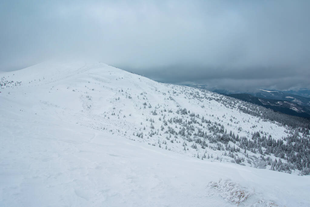 Ongelooflijk winterlandschap. bergen bedekt met sneeuw en blauwe bewolkte lucht - Foto, afbeelding