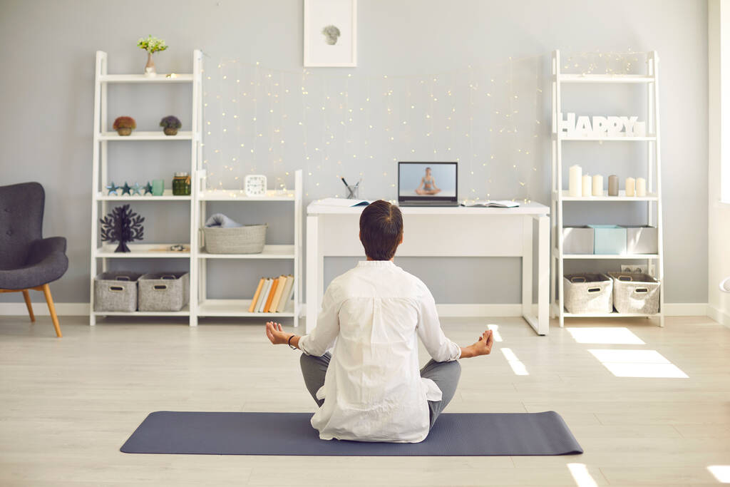 Mulher sentada no tapete de fitness e meditando repetindo ioga asana após professor on-line no laptop - Foto, Imagem