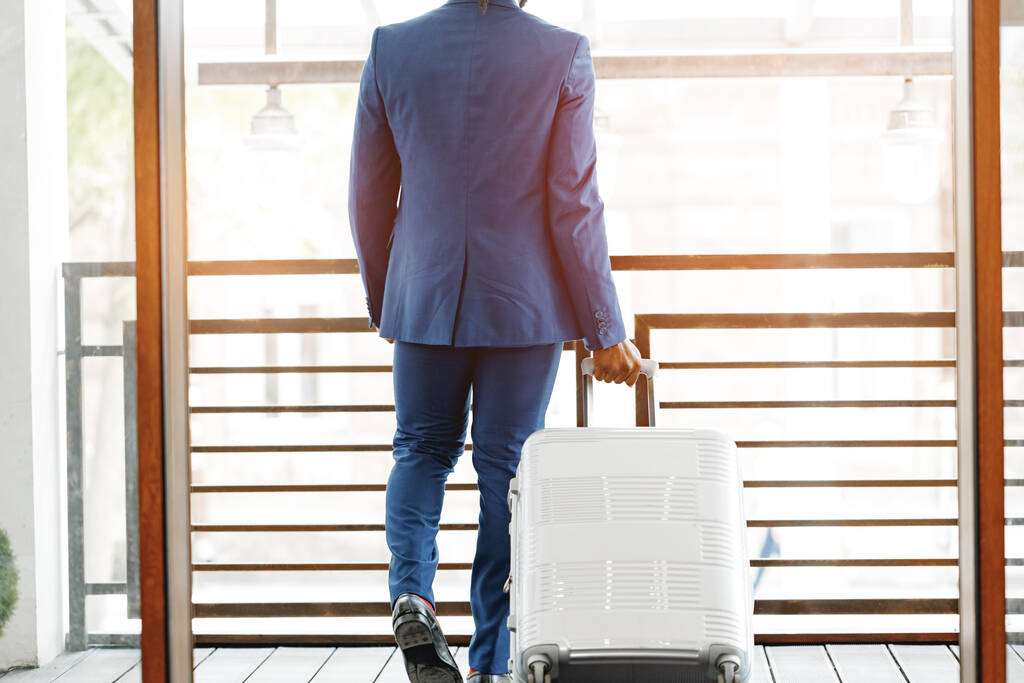 Onherkenbare zakenman met bagage koffer in hotellobby - Foto, afbeelding