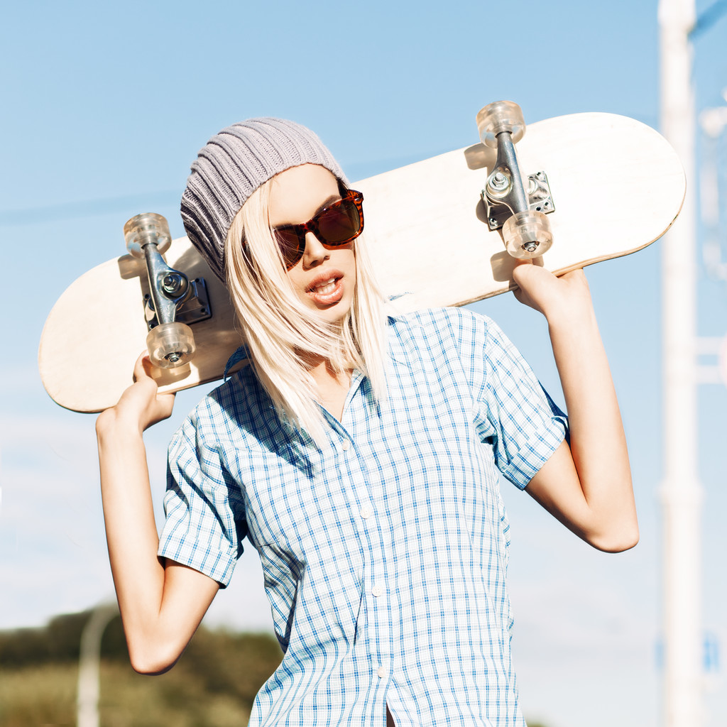 Beautiful blonde girl in short shorts with skateboard - Photo, Image
