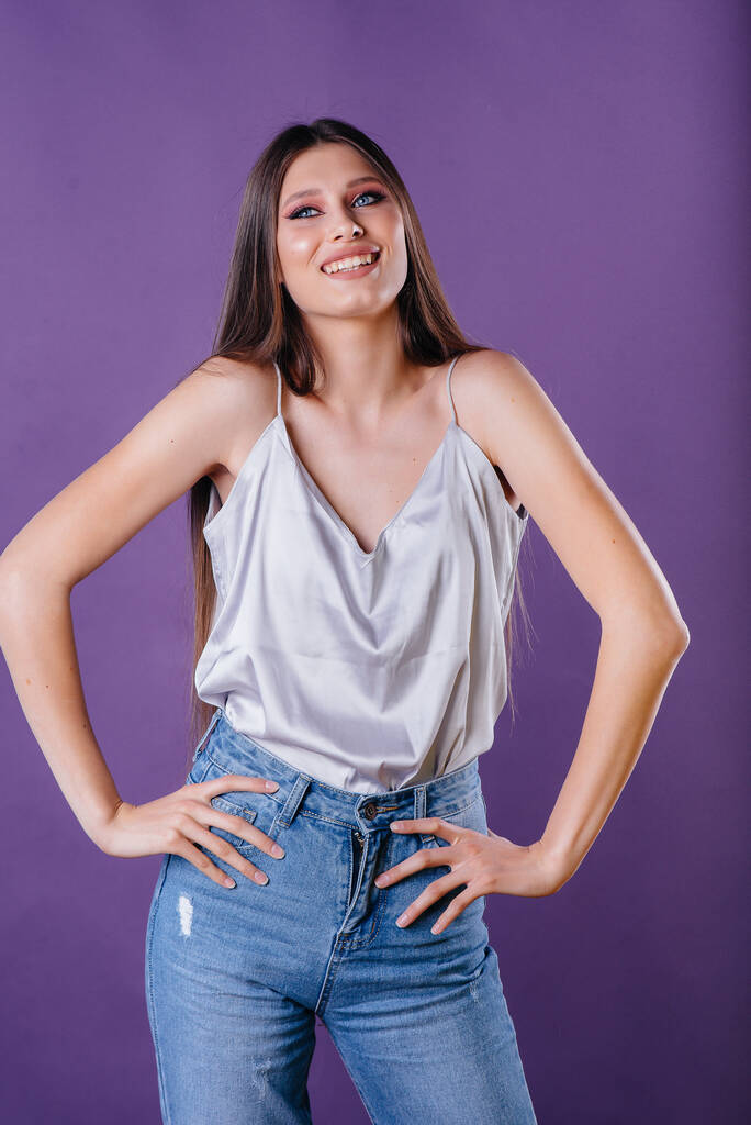 Una giovane bella ragazza mostra emozioni e sorrisi nello Studio su uno sfondo viola. Ragazze per la pubblicità - Foto, immagini