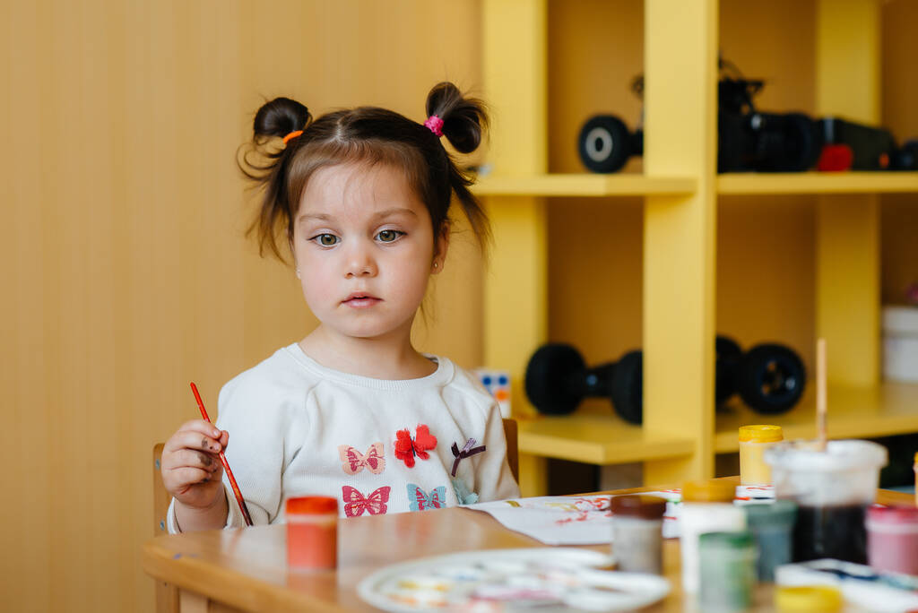 A cute little girl is playing and painting in her room. Recreation and entertainment - Photo, Image