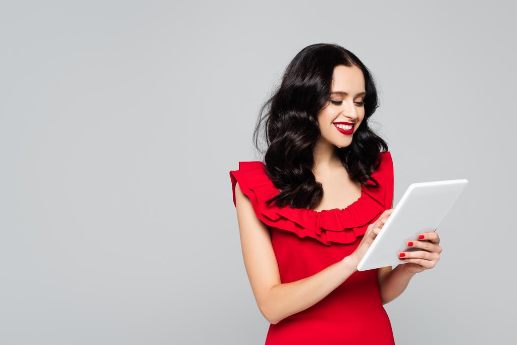весела жінка з червоними губами за допомогою цифрового планшета ізольована на сірому
 - Фото, зображення