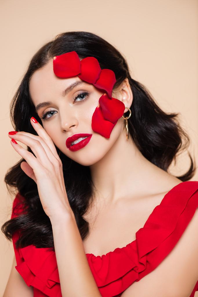 bella giovane donna con petali di rosa rossa sul viso isolato su rosa - Foto, immagini