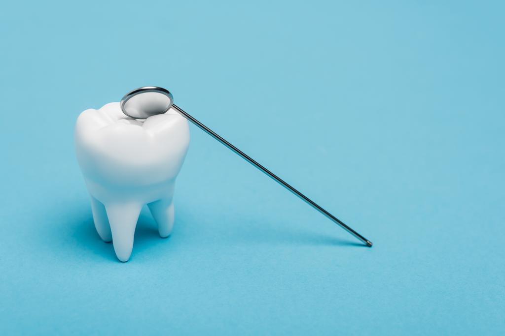 Model zęba i lusterko dentystyczne na niebieskim tle - Zdjęcie, obraz