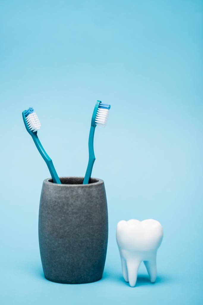 Tandenborstels en tandenmodel op blauwe achtergrond - Foto, afbeelding