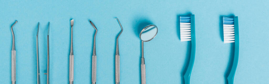 青の背景に歯科用ツールや歯ブラシのトップビュー、バナー  - 写真・画像
