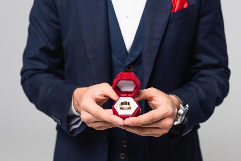 vista ritagliata di uomo elegante portagioie con anello di nozze isolato su grigio - Foto, immagini
