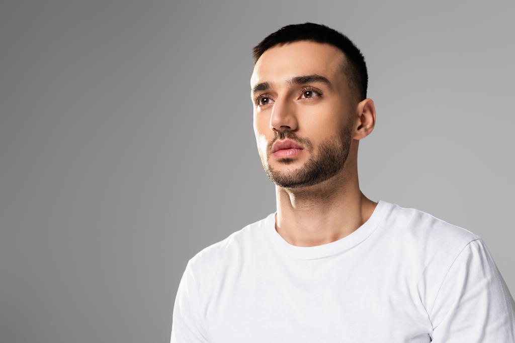 confident, brunette hispanic man in white t-shirt looking away isolated on grey - Photo, Image