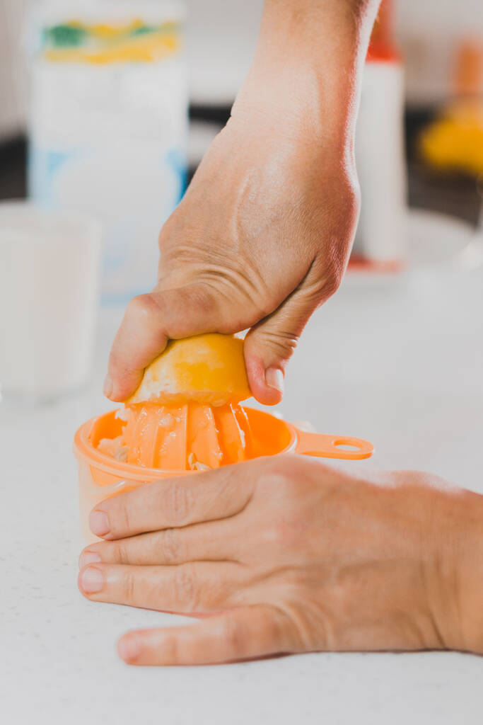 Spremere il limone a mano con gli spremiagrumi in cucina - Foto, immagini