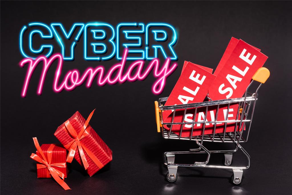 rode geschenken in de buurt van speelgoed kar met verkoop tags in de buurt van cyber maandag belettering op donkere achtergrond, zwarte vrijdag concept - Foto, afbeelding