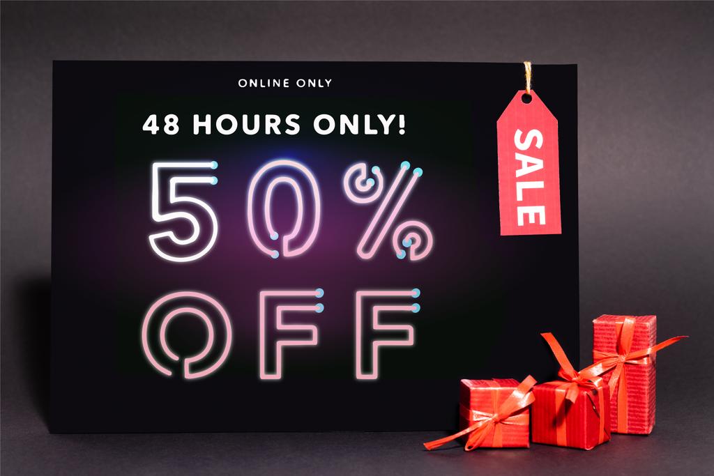 placard csak online, 48 óra, 50% kedvezmény a betűk és eladási címke közelében ajándékok sötét háttér - Fotó, kép