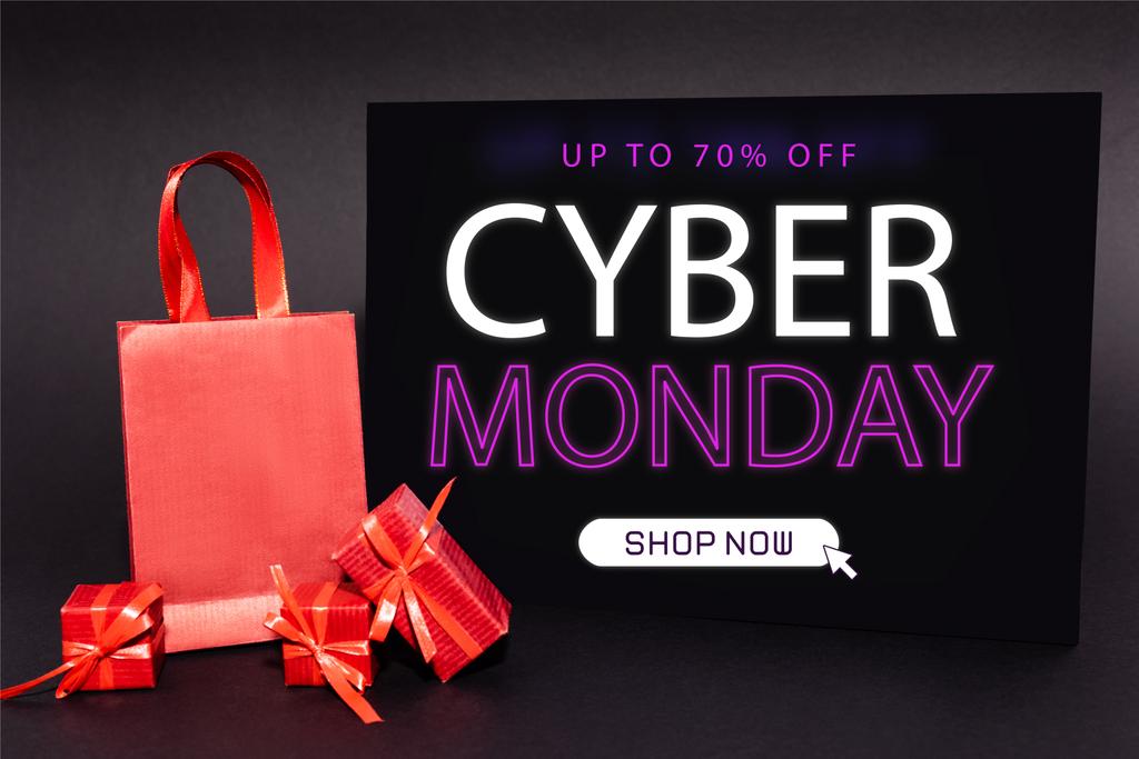 Rote Geschenke und Einkaufstüten in der Nähe von Plakaten mit bis zu 70 Prozent Rabatt, Cyber Monday, jetzt Schriftzug auf dunklem Hintergrund - Foto, Bild