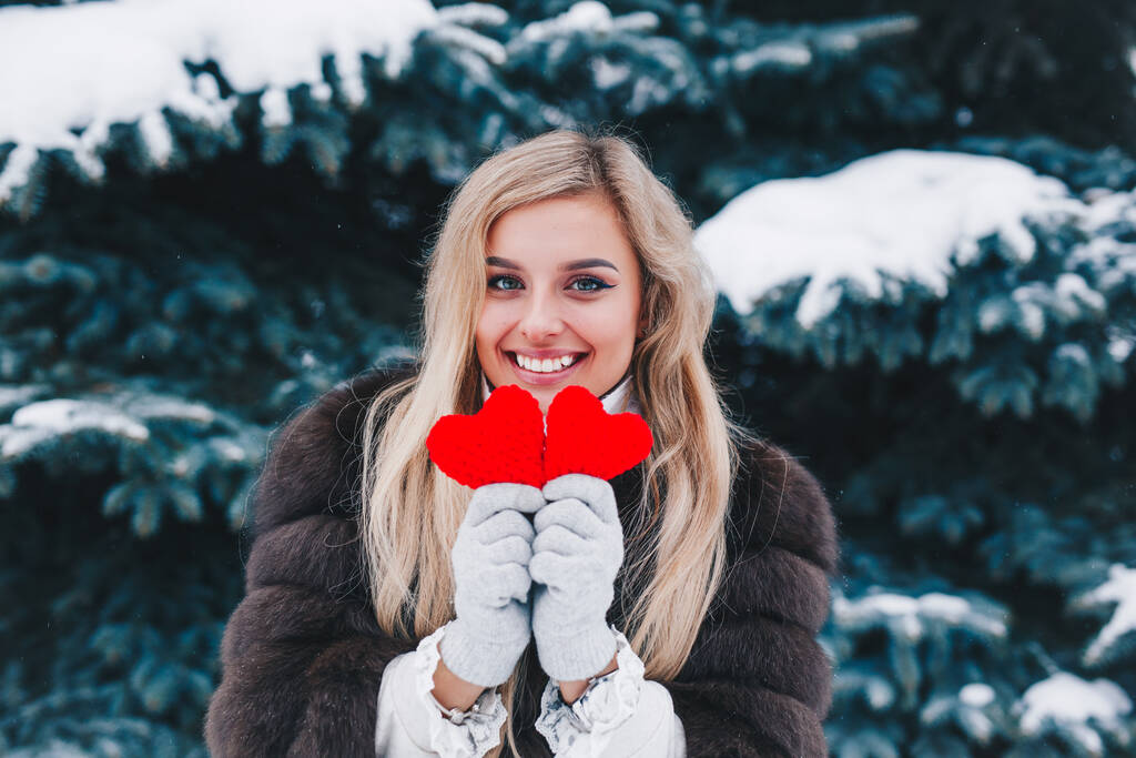 Valentinstag. Schön lächelnde Frau mit roten Herzen in den Händen im Wald . - Foto, Bild