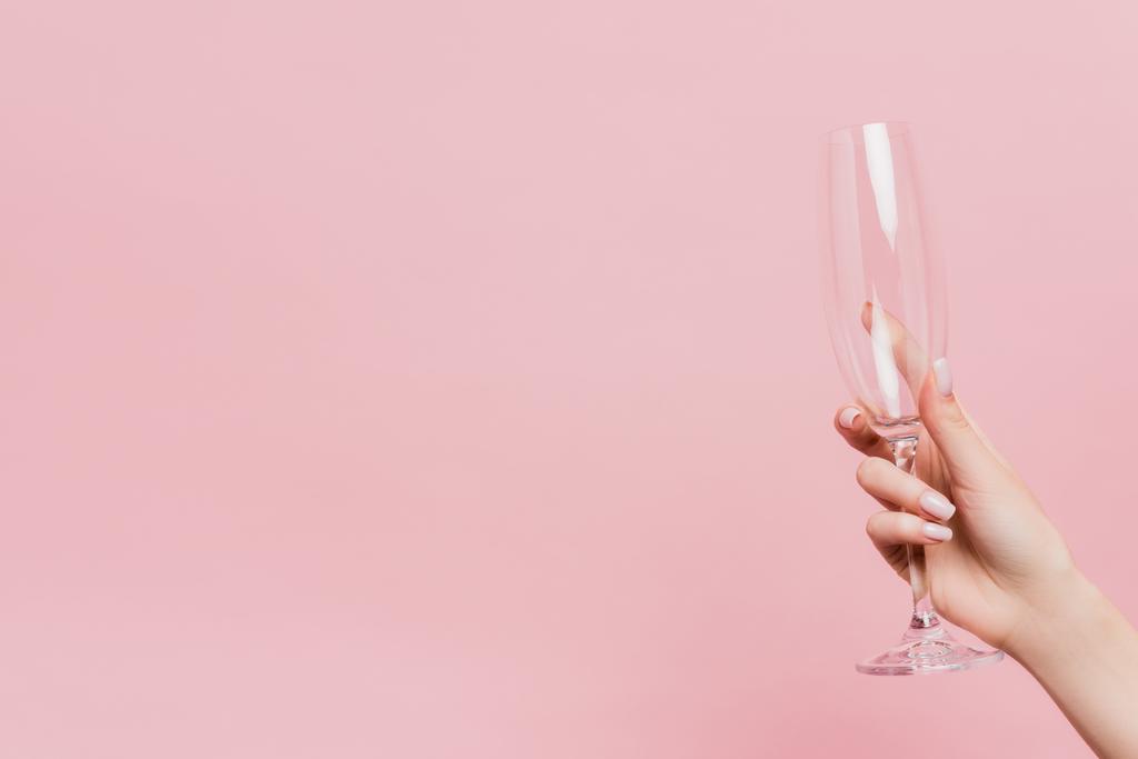 обрезанный вид женщины, держащей пустой бокал шампанского изолирован на розовый - Фото, изображение