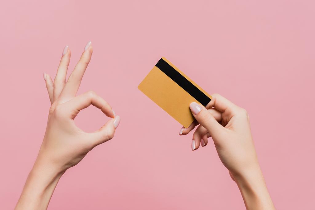 vista parcial de la mujer en posesión de la tarjeta de crédito y mostrando signo ok aislado en rosa - Foto, Imagen