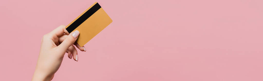 vista parcial de la mujer que sostiene la tarjeta de crédito aislada en rosa, bandera - Foto, imagen