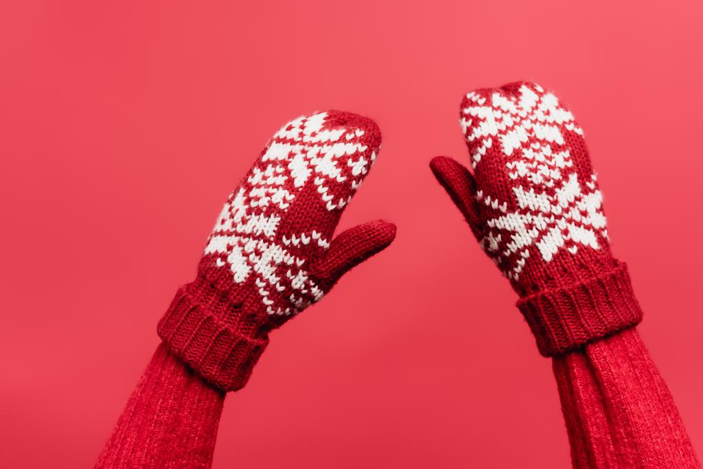 καλλιεργημένη άποψη των γυναικείων χεριών σε ζεστά γάντια που απομονώνονται σε κόκκινο - Φωτογραφία, εικόνα