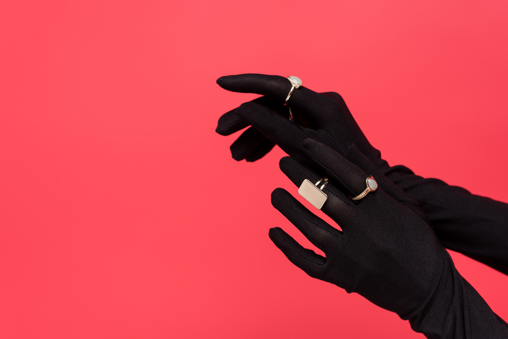 cropped view of female hands in black gloves with golden rings isolated on red - Photo, Image